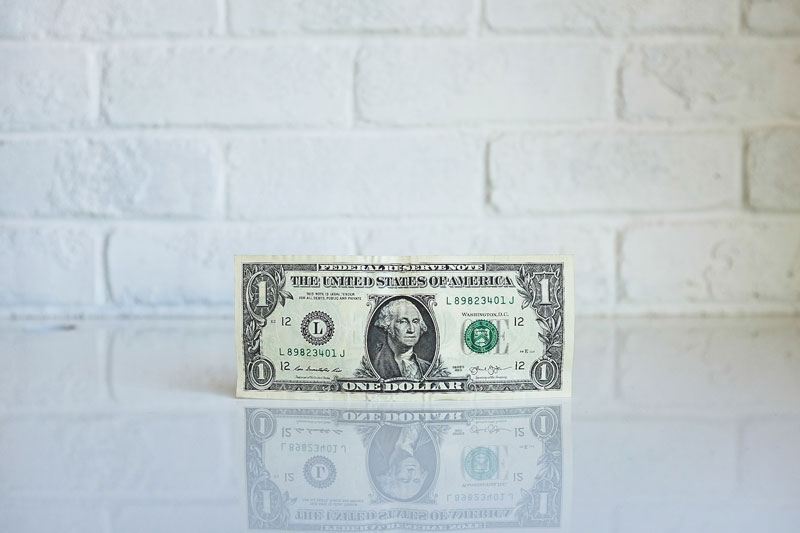 A dollar bill placed upright on a table.