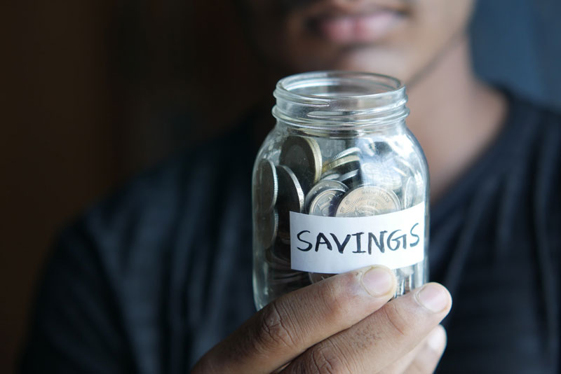 A person holding a jar full of coins.