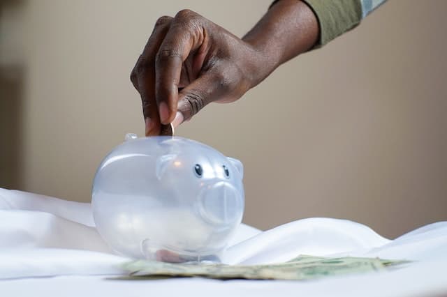 A person putting money in a piggy-bank.